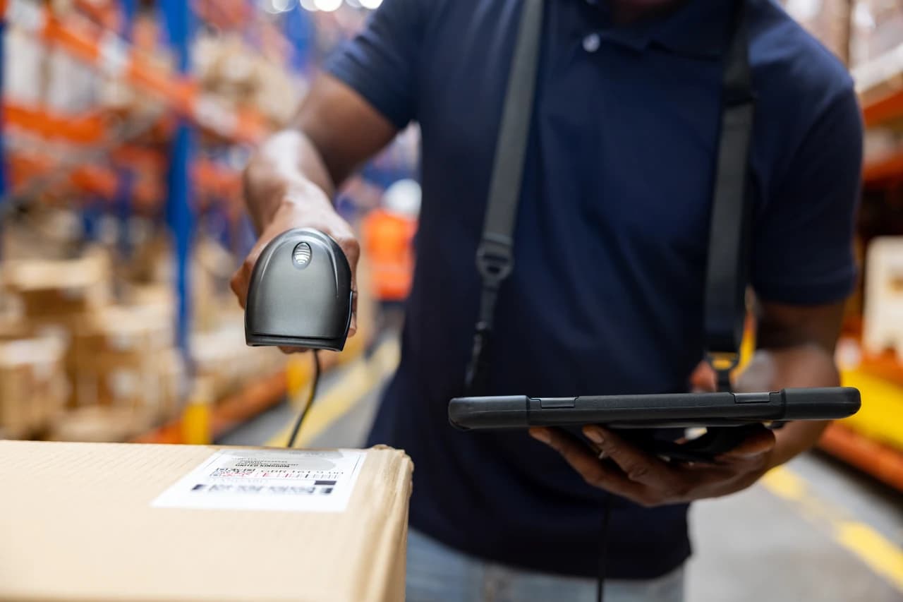 A worker scanning a labelled carton with a handheld barcode scanner